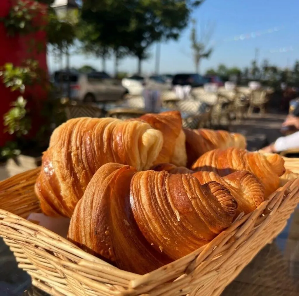 Panier de croissants dorés servis en terrasse au petit déjeuner