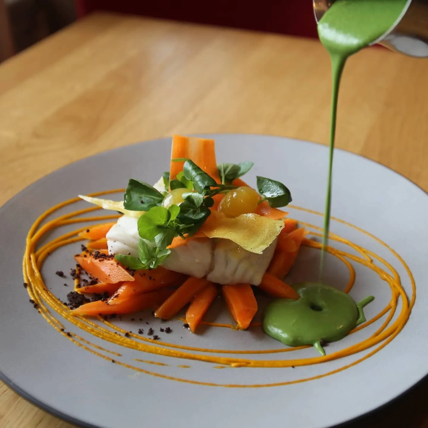 Sauce verte versée sur un dos de cabillaud aux carottes