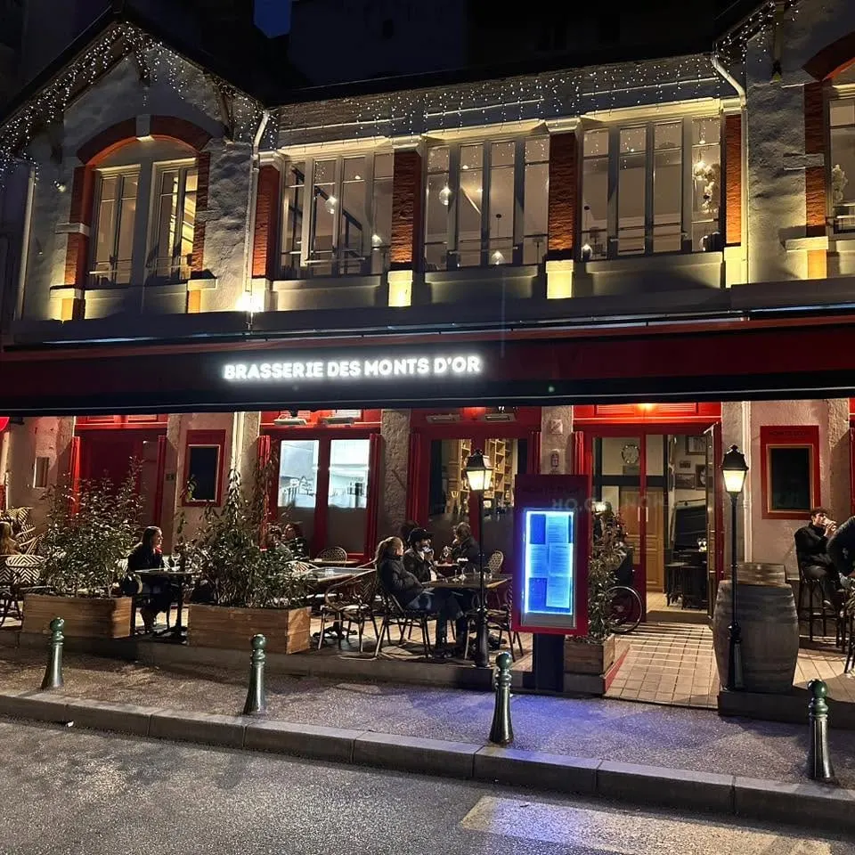 La façade illuminée de nuit et la terrasse animée