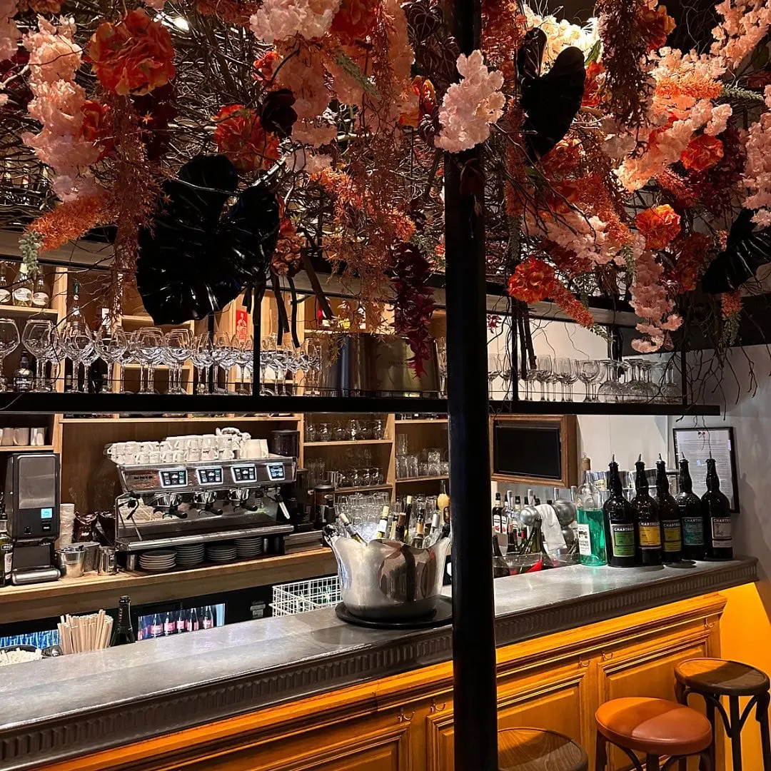 Le comptoir du bar et sa cave à liqueurs, sous les fleurs