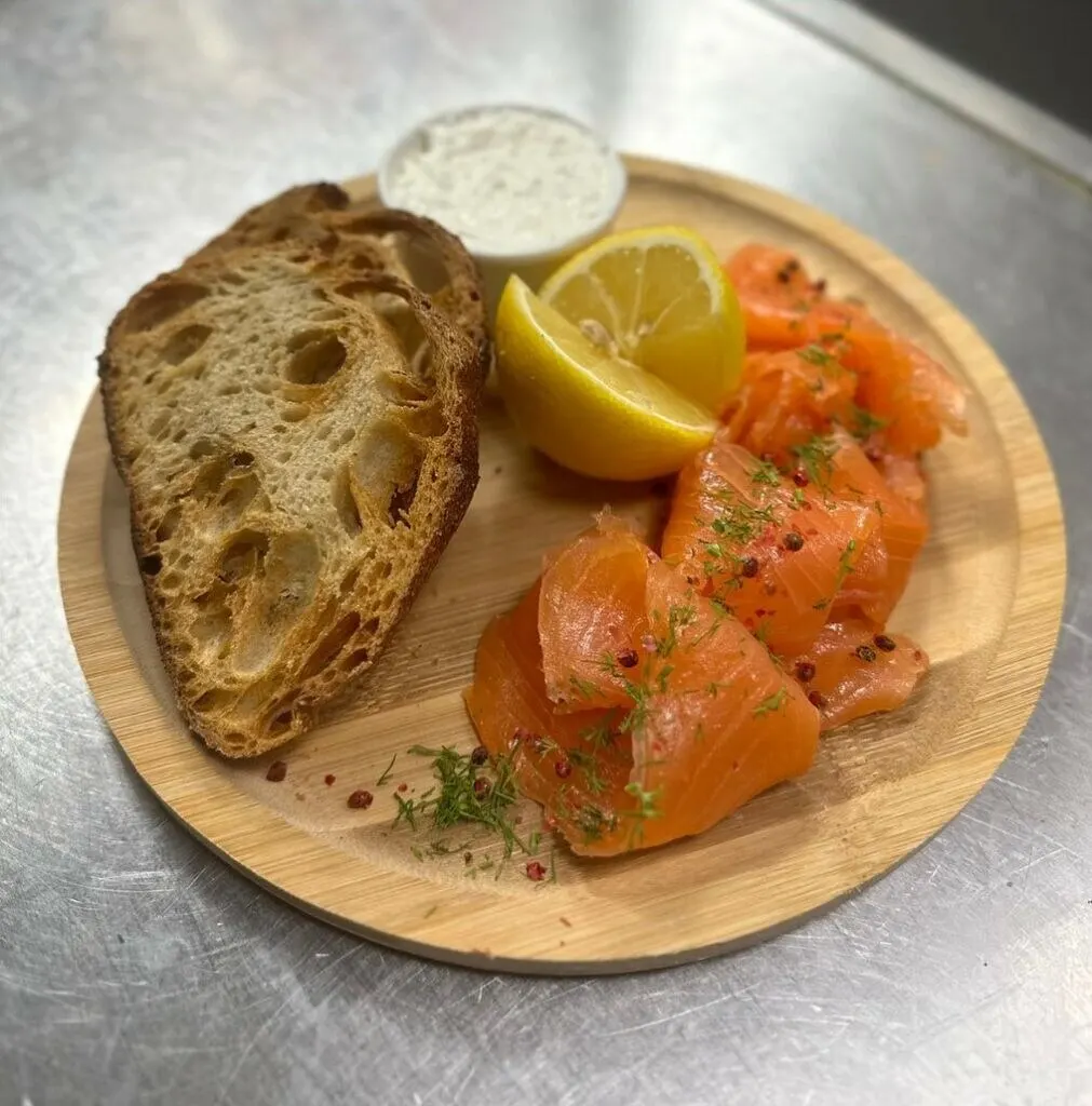 Saumon fumé tranché, pain de campagne toasté et citron sur planche de bois