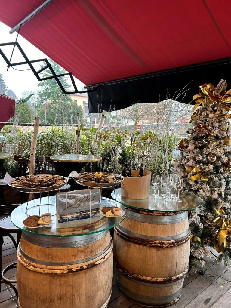 La terrasse de la brasserie décorée pour les fêtes, tonneaux et sapins givrés sous le store rouge